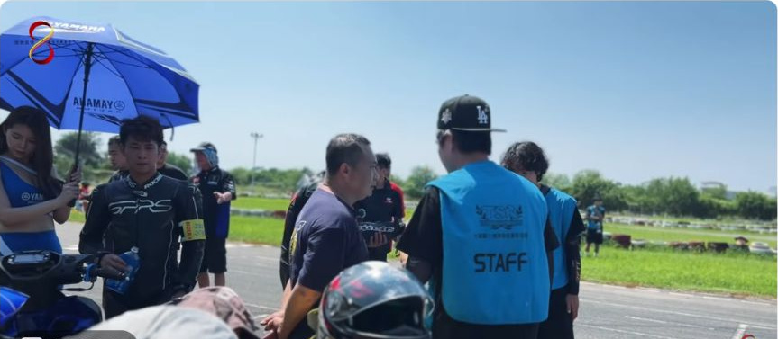 原影片約00:17實際畫面。原片四小時耐久賽場邊實際畫面,選手、車輛與工作人員共同入鏡。