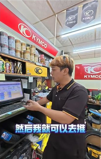 原片約00:23，受訪者在店內電腦旁接續說明維修紀錄的用途。